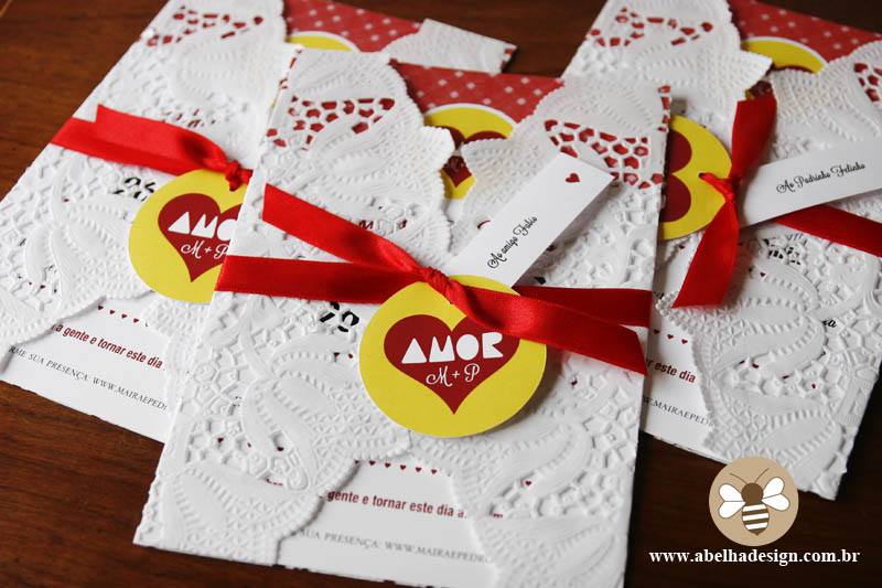 Convite de casamento Abelha Design: envelope em renda, fita vermelha e tag da paçoça Amor.