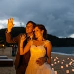 Casamento na praia Tabi e Carlos: noivos na areia com velas de noite em luau. Foto: André Pinnola